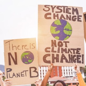 people holding brown climate protest signs in the air