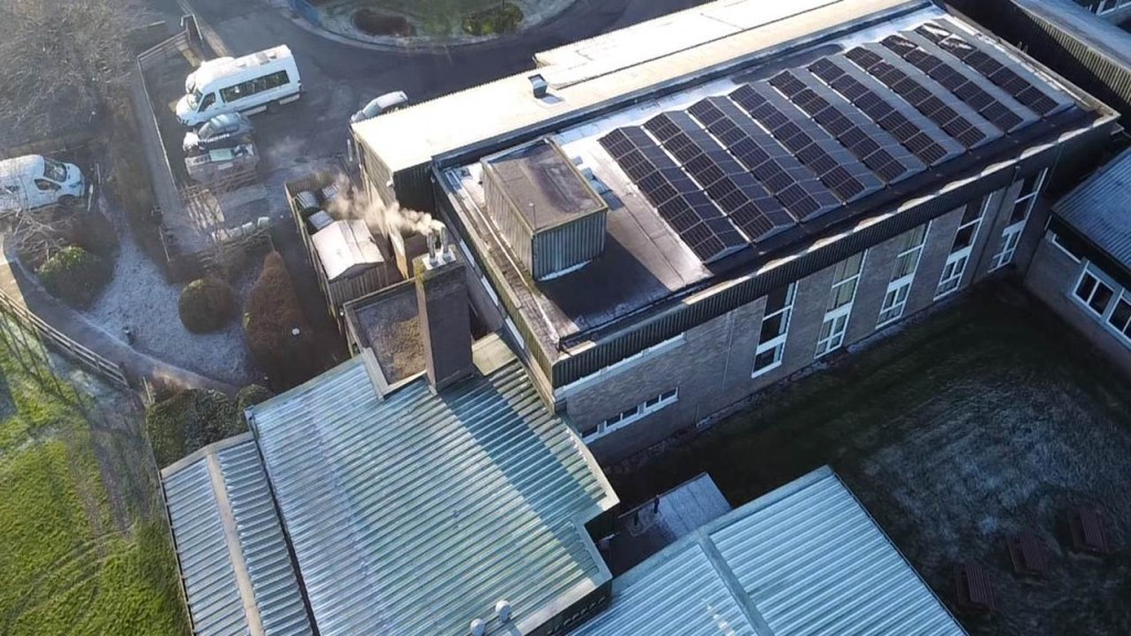 Birds-eye angle of school with solar panel roof as the main focal point of the image.